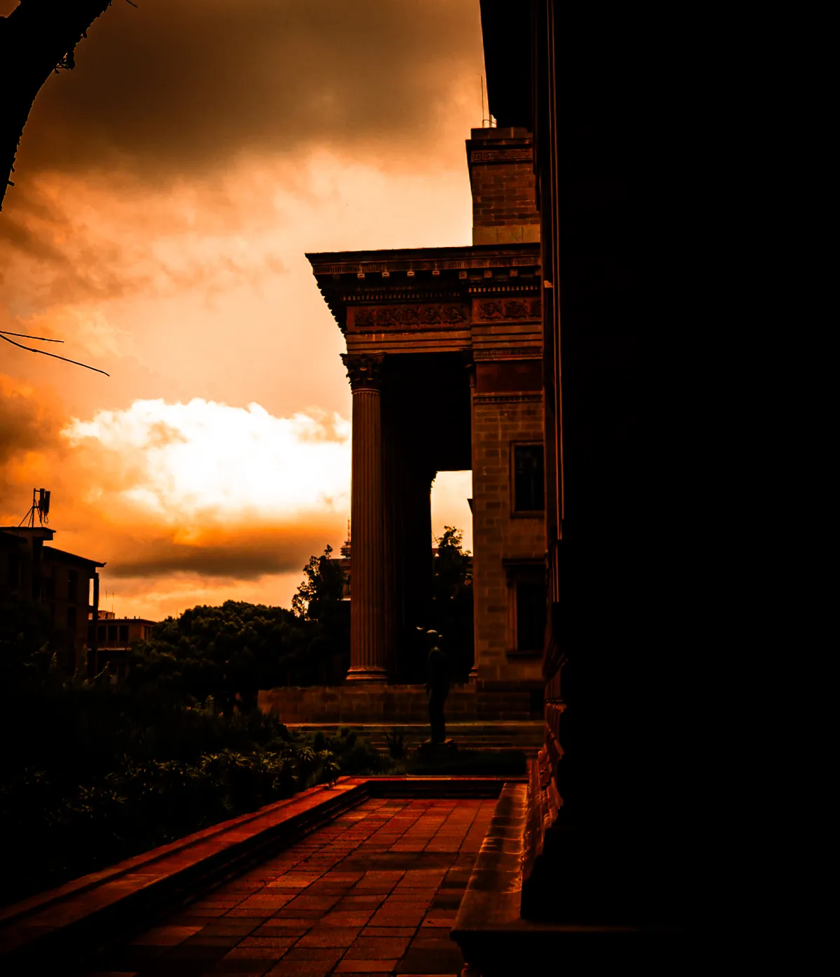 Columns of a sandstone hall under an orange storm sky, by Tha'Bang Studios