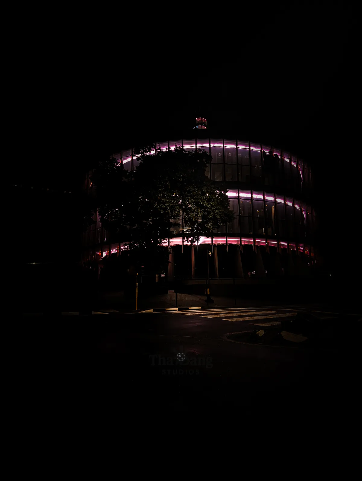 A round glass building lit pink at night, by Tha'Bang Studios